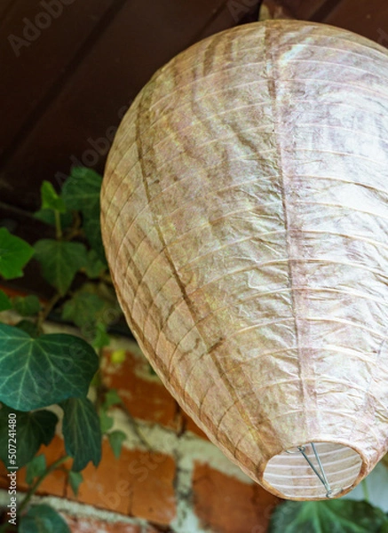 Fototapeta Fake wasp nest to scare dangerous insects away from home. A paper ball in the form of real wasp nest under roof in the garden.