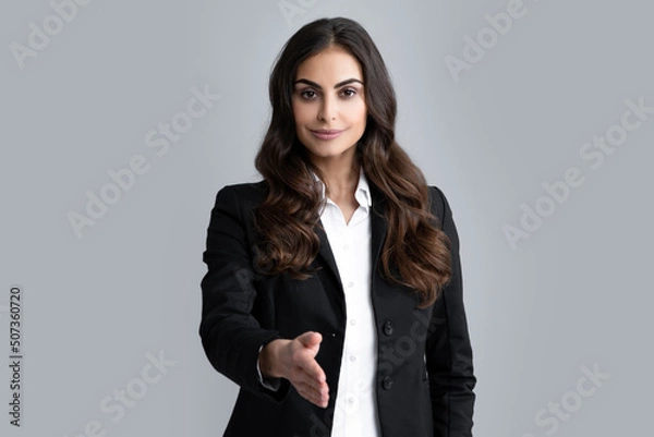 Obraz Business woman in suit smiling friendly offering handshake as greeting and welcoming. Successful business. Businesswoman giving a handshake. Friendly offering handshake as greeting and welcoming.