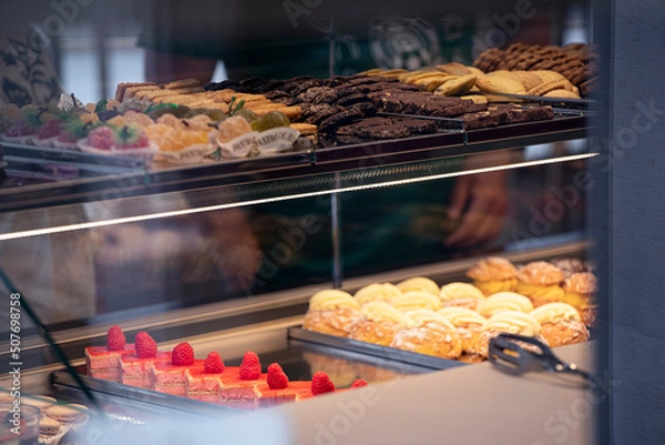 Fototapeta Italian Pastries On Display of Confectionery Shop Stock Photo, sweet desserts view by the window of cafe.
