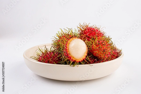 Fototapeta Rambutan fruit on ceramic white plate on white table background.