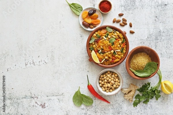Fototapeta Vegan Moroccan Bulgur with Chick Peas, spinach, dried apricots and date fruit. Traditional African Tajine dish. Flat layot