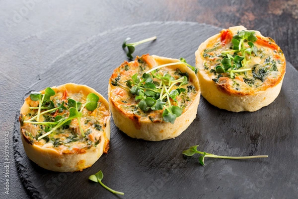 Obraz Savoury mini quiches with custard and watercress on a black round wooden board
