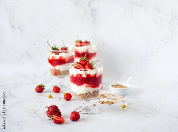 Obraz Italian strawberry tiramisu dessert with mascarpone and whipped cream, savoyardi crumb and fresh strawberry in glass on marble. Recipe of simple dessert, cheesecake, pudding or berry trifle cake.