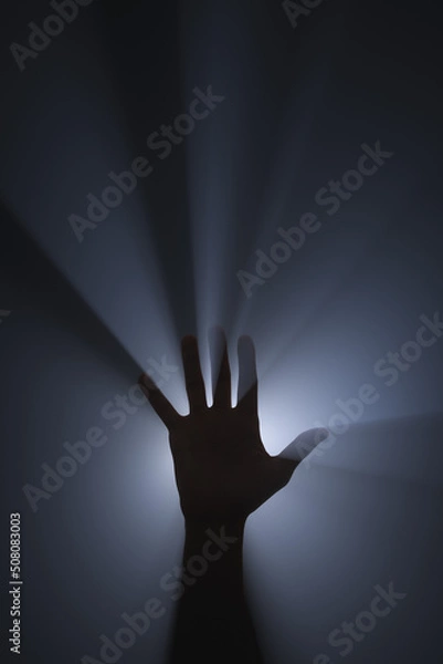 Fototapeta Raised hand. Source of bright light behind the hand