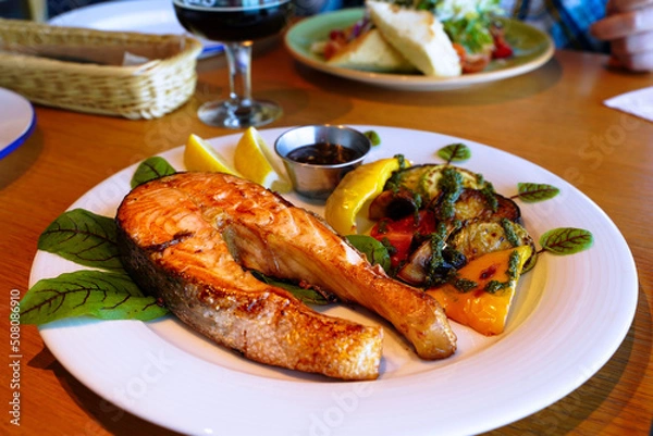 Fototapeta Fried salmon with lemon and vegetables. Serving the dish. Shallow depth of field
