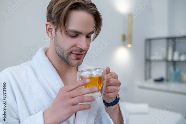 Obraz Young man in a white robe holding a cup of tea