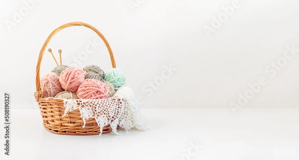 Fototapeta Basket with balls of thread and knitting needles on a white background with copy space. Crochet, knitting as a hobby.