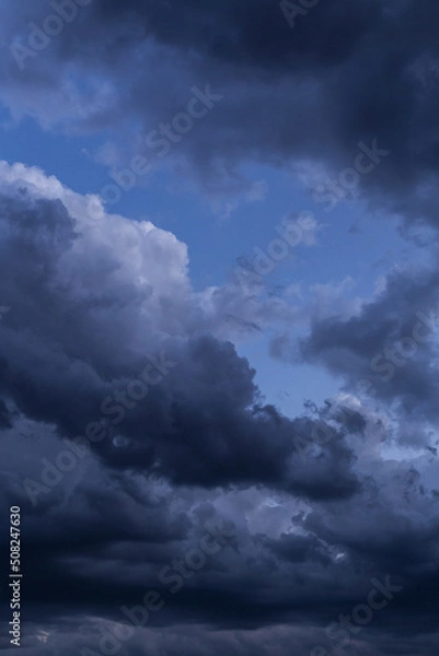 Fototapeta Epic Dramatic storm dark grey cumulus rain clouds against blue sky background texture, thunderstorm
