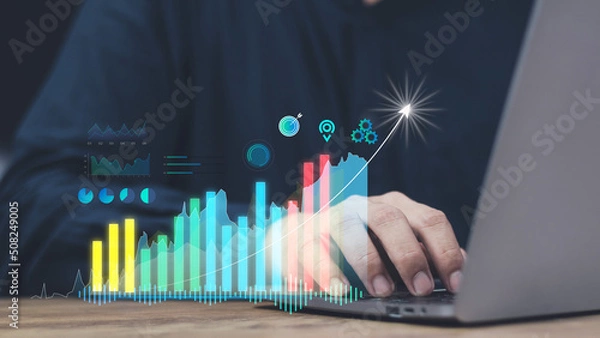 Fototapeta financial and investment technology concept,man's hand using computer to analyze graphs and charts of stock market digital assets gold and oil to be in line with the volatility of the world economy