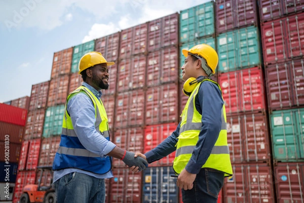 Obraz Dock manager and engineer worker shake hand with smile in shipping container yard. Import and export product. Manufacturing transportation and global business concept. Successful on porject