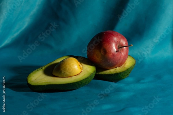 Fototapeta avocado and apple on a blue background