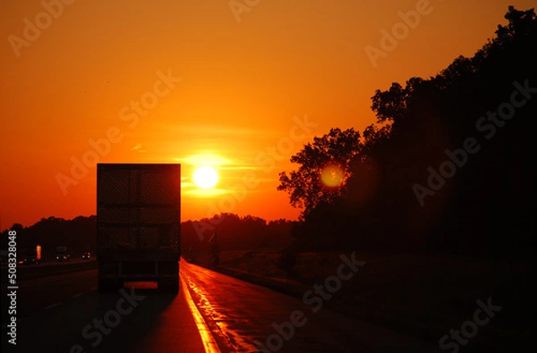 Obraz In the Midwest, USA. A semi truck on the highway as the sun is setting.