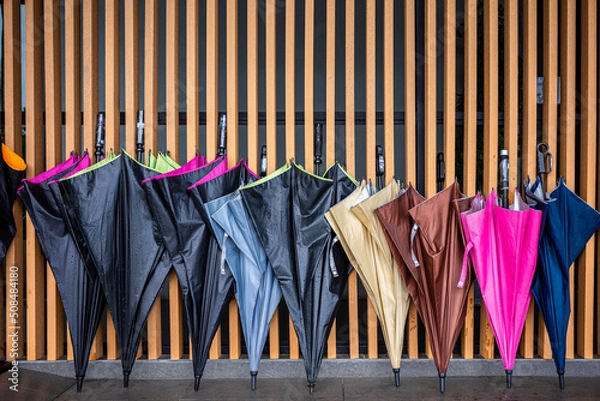 Obraz Wet umbrellas leaning on wooden wall for drying.