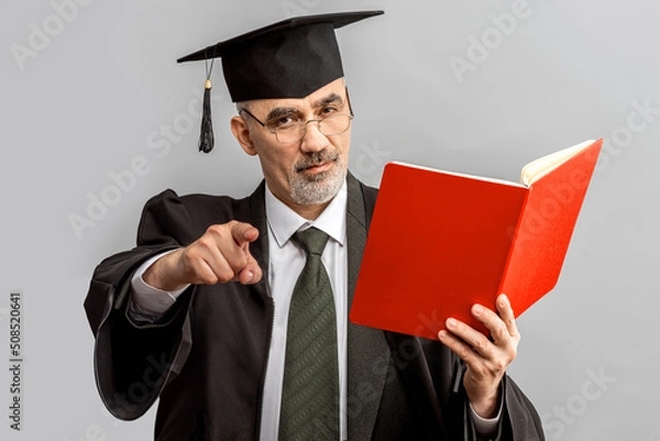 Fototapeta Academician, Professor, Prof is wearing a cap with Tassel and black gown. Senior educator or Doctor of Philosophy, learned man from a university or college