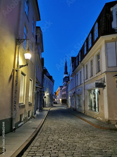 Obraz A narrow cobbled street in the Old City, at the end of which you can see the spire of the Church of the Holy Spirit against the blue sky. Old Tallinn.