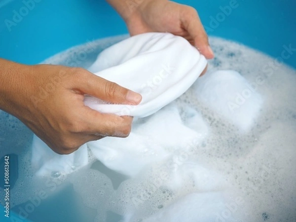 Obraz Woman hands washing white clothes in sink. closeup photo, blurred.