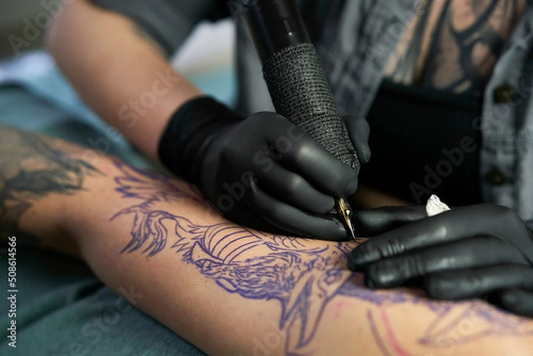 Obraz Close up of tattoo artist drawing on arm of client