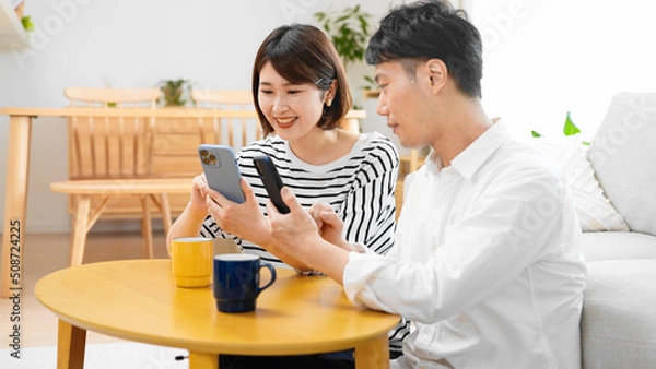 Fototapeta 部屋でスマートフォンを操作する男性と女性
