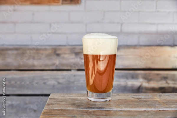 Obraz A pint of beer on a wooden bench on a patio