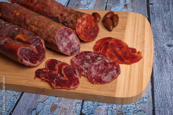 Fototapeta Iberian sausage, Iberian chorizo and Iberian loin on cutting board and blue wooden table.