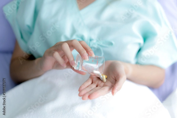 Obraz Hand taking pills to treat sickness at the hospital.