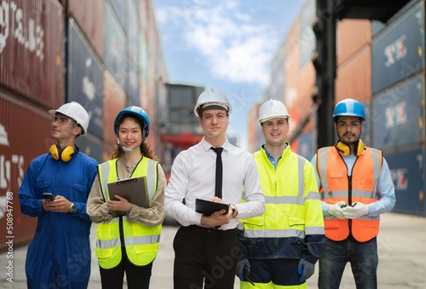 Obraz Group of engineer worker and manager standing in the shipping yard container. Truck lifting and forklift behind. Import, export product. Manufacturing transport and global business concept