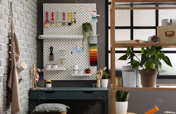 Fototapeta Stylish decorator's workplace with modern tools and shelf unit in workshop