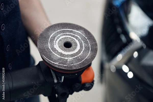 Obraz Car polishing circle close-up. Polishing paste on a polishing wheel. Polishing the car. Professional car detailing. Worker with orbital polisher in auto repair shop
