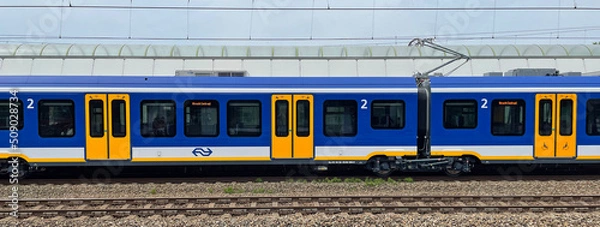 Obraz Weesp, the Netherland - June 5, 2022: Side view of a Dutch public transport train standing in a railway station.