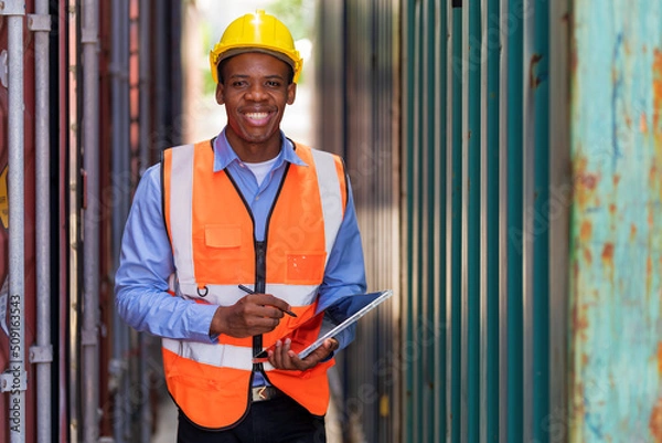 Obraz African worker using tablet working at container yard warehouse.