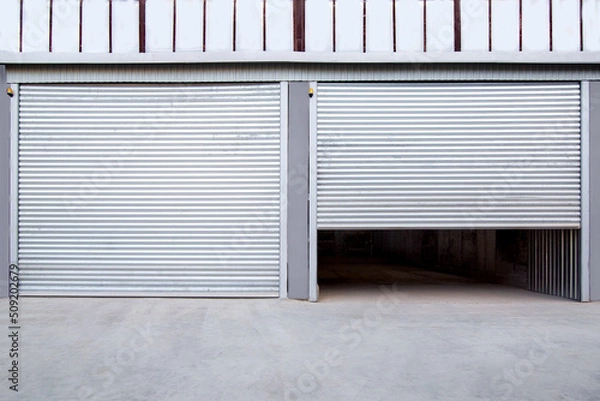 Fototapeta 2 gray iron shutter door? of garage and industrial building warehouse exterior facade with grey concrete road, front view on closing gate nobody.