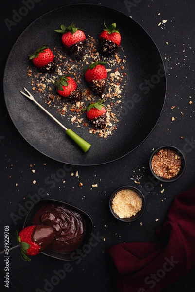 Obraz Dessert with chocolate covered strawberries on  black plate on  black background, top view.
