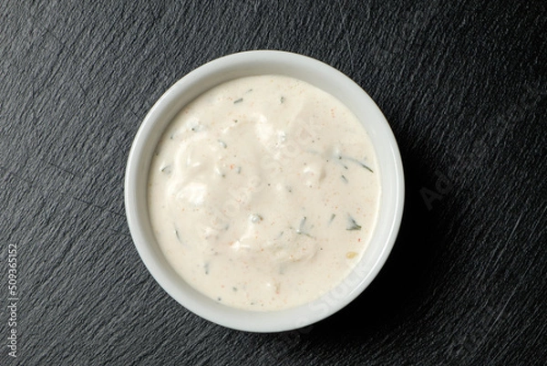 Fototapeta Garlic sauce in bowl on a slate slab on black background