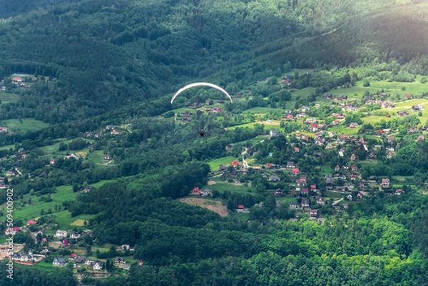 Fototapeta Paraglider on the background of mountains. Houses in the background. Międzybrodzie Bialskie, Poland.