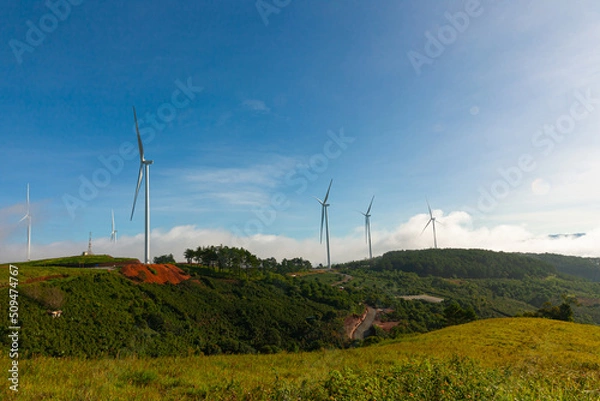 Fototapeta Renewable energy wind turbines windmill isolated on the beautiful blue sky, white clouds and on the tea fields in Da Lat city, Lam Dong, Viet Nam