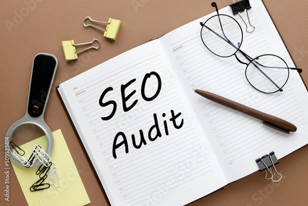 Fototapeta SEO AUDIT. Business concept. open notepad. text on white paper. brown background