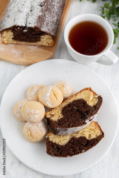 Fototapeta Lemon chocolate cupcake and cookies in a plate, a cup of tea on a light table.