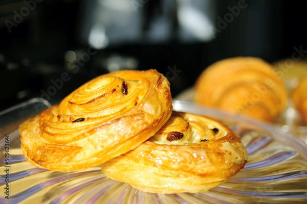 Fototapeta Cinnamon rolls pastry with small pieces of resins on  glass plate in the coffee shop