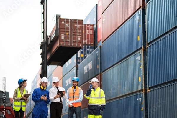 Obraz Group of engineer worker and manager standing in the shipping yard container. Truck lifting and forklift behind. Import, export product. Manufacturing transport and global business concept