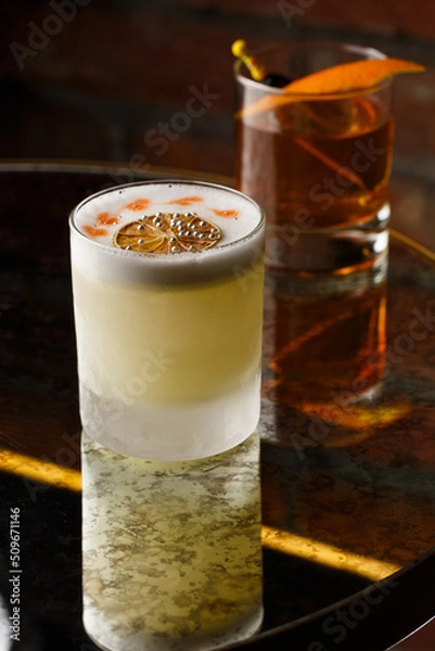 Fototapeta Pisco sour cocktail - whiskey with lime, egg white, sugar syrup in glass on dark background. Space for text
