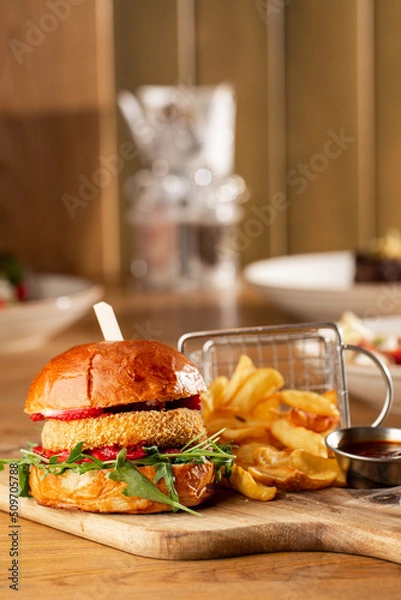 Fototapeta Big cheeseburger with french fries. Hamburger with beef patty onion, tomato, lettuce pickles, melted cheddar, mustards, tomato jam, mayo