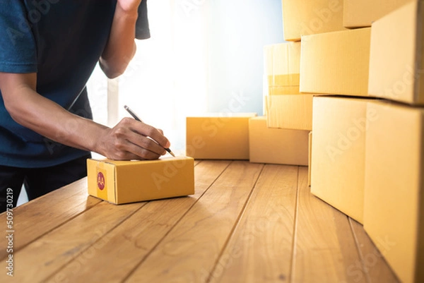 Fototapeta Shipment Online Sales .Man worker delivery service and working packing box, business owner working checking order to confirm before sending customer in post. Online selling, e-commerce Start up.