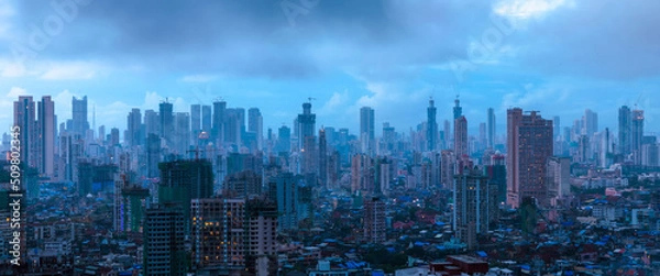 Fototapeta A cinematic evening in Mumbai when the sky was overcast with dark monsoon clouds about to burst over the city, and the dazzling city lights started coming alive in the mystic blues of twilight. 