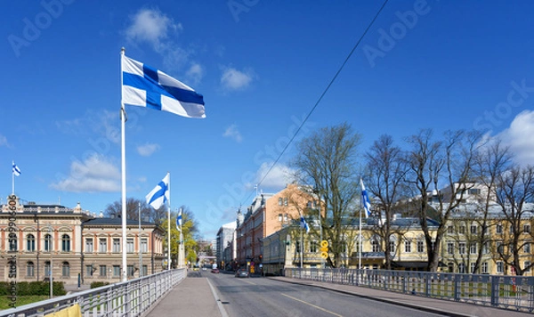 Fototapeta On official flag days, Finnish flags fly everywhere in the city. The city is still quiet on a Sunday morning before the shops open. Photo taken in Turku, Finland.