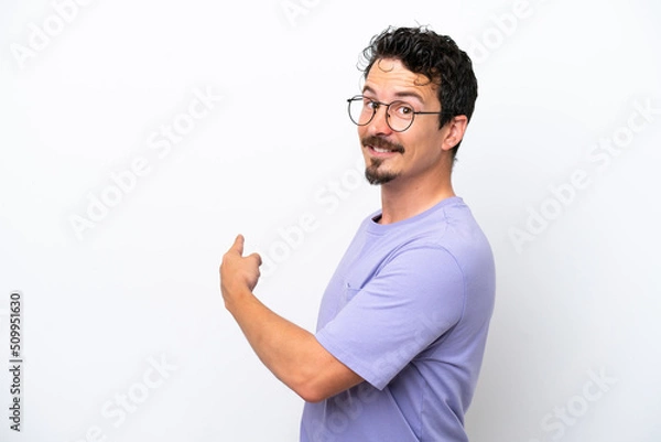 Fototapeta Young man with moustache isolated on white background pointing back