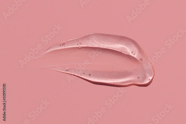 Fototapeta Gel texture smear stroke on pink background, skin care product snail mucin or moisturiser serum swatch