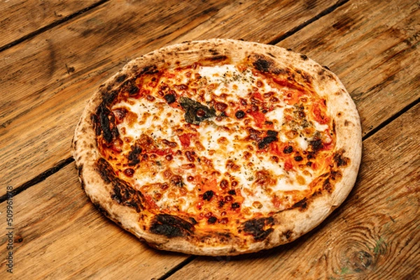 Fototapeta Pizza food background. Homemade Neapolitan pizza Margherita with mozzarella cheese and tomato sauce on a rustic wooden table. Italian food.