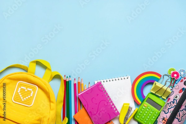 Fototapeta Back to school, education concept Yellow backpack with school supplies - notebook, pens, eraser rainbow, numbers isolated on blue background Top view Copy space Flat lay composition