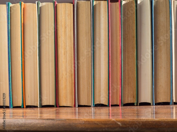 Obraz A row  of old hardcover books. Books on a wooden shelf, turned back cover. Books from the Home Library