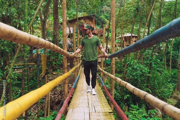 Obraz man crossing bridge in forest